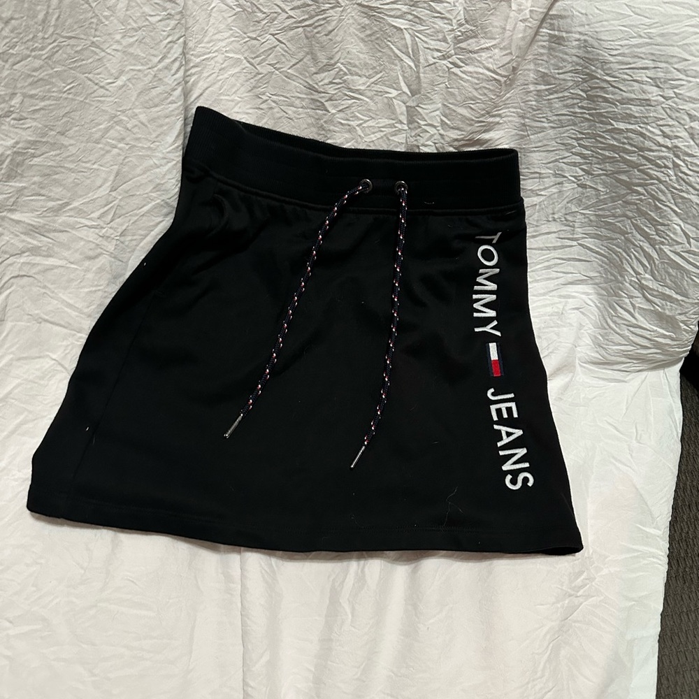 A tommy jeans Hilfiger skirt with two blue red and white strings in the front.